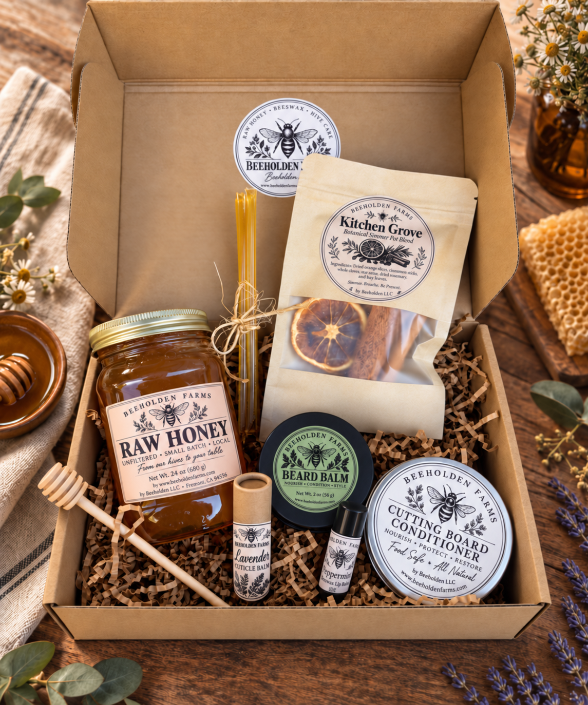 Beeholden Farms Hive & Hearth gift box with a jar of raw honey, Kitchen Grove simmer pot blend, beard balm, cutting board conditioner, lavender cuticle balm, peppermint lip balm, honey sticks, and a wooden honey dipper in kraft crinkle fill.