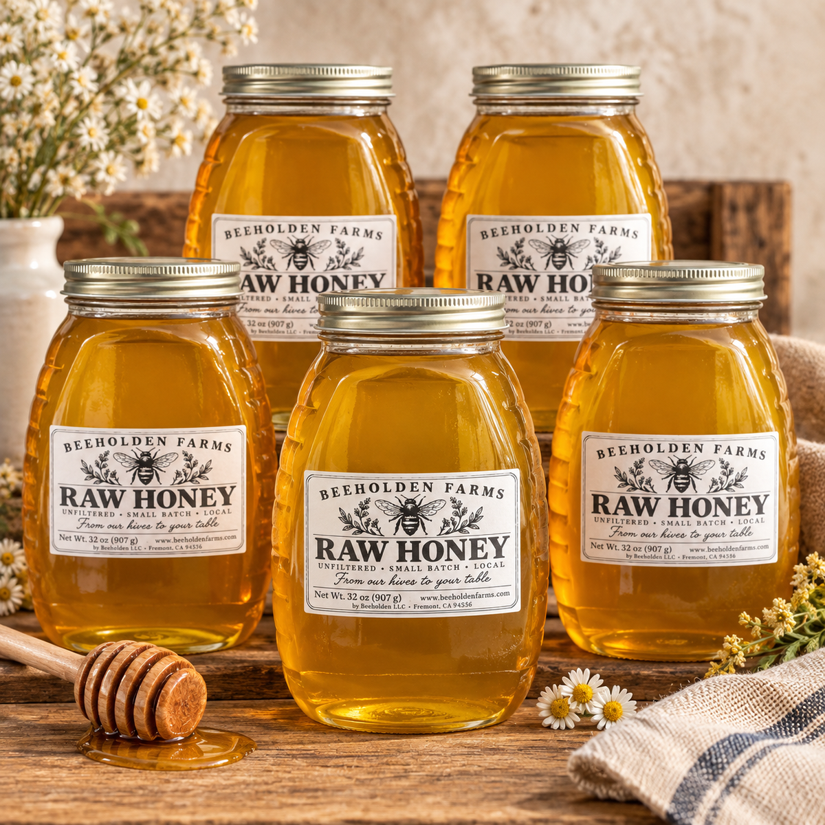 Five 32 oz jars of Beeholden Farms raw honey on a rustic wooden table with daisies and a honey dipper