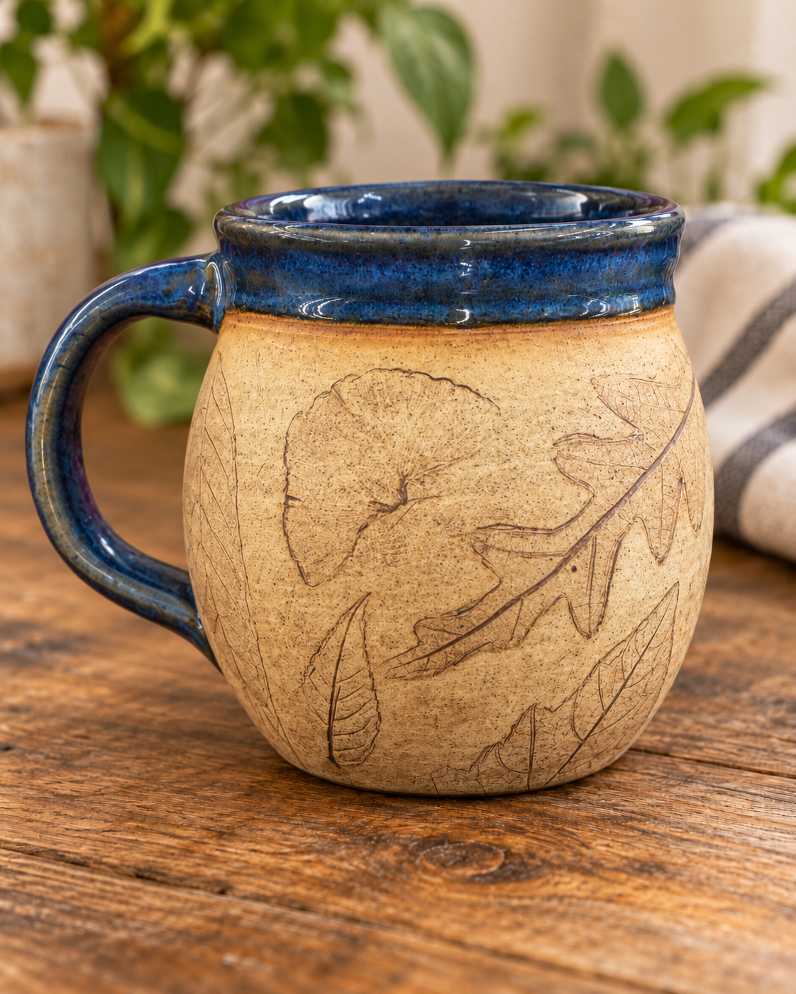 Back of the leaf-print pottery mug showing ginkgo, oak and smaller leaf impressions in speckled clay