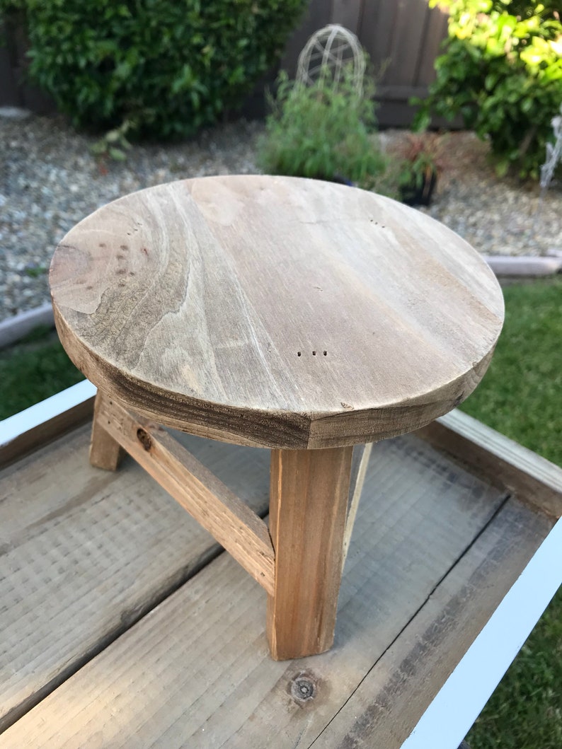 Top of a round wooden stool plant stand showing natural light brown wood grain